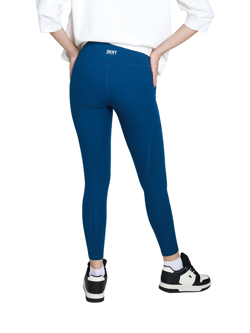 Mujer vistiendo leggings deportivos DKNY color azul Poseidon de cintura alta y largo 7/8.