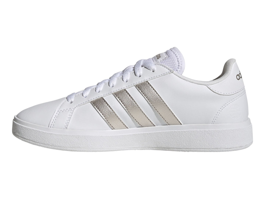 Tenis Adidas blancos con franjas laterales en color plata metálico y suela blanca.