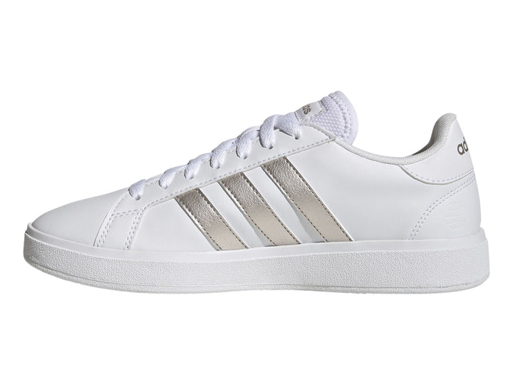 Tenis Adidas blancos con franjas laterales en color plata metálico y suela blanca.