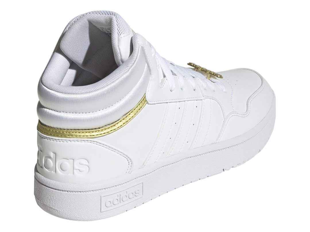 Tenis Adidas Hoops 3.0 Mid en color blanco con detalles metálicos dorados y suela blanca.