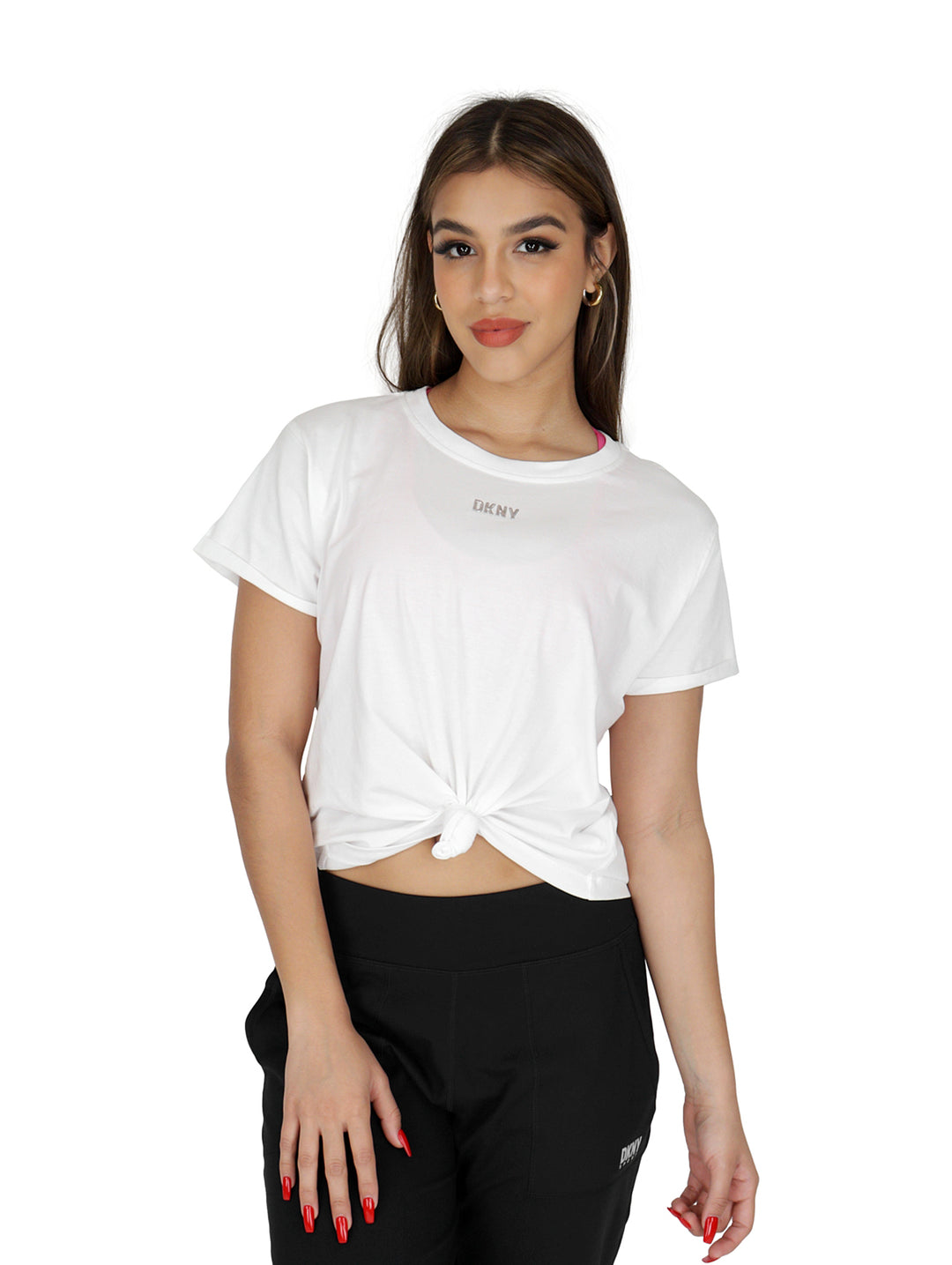 Mujer vistiendo una playera blanca DKNY de corte boxy con nudo frontal y logo metálico en el pecho.