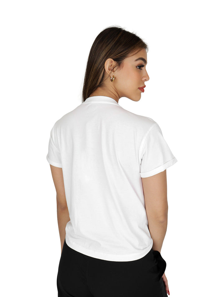 Mujer vistiendo una playera blanca DKNY de corte boxy con nudo frontal y logo metálico en el pecho.