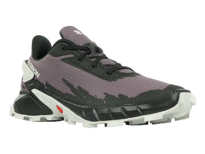 Tenis deportivos Salomon color morado y negro con suela blanca y detalles rojos.