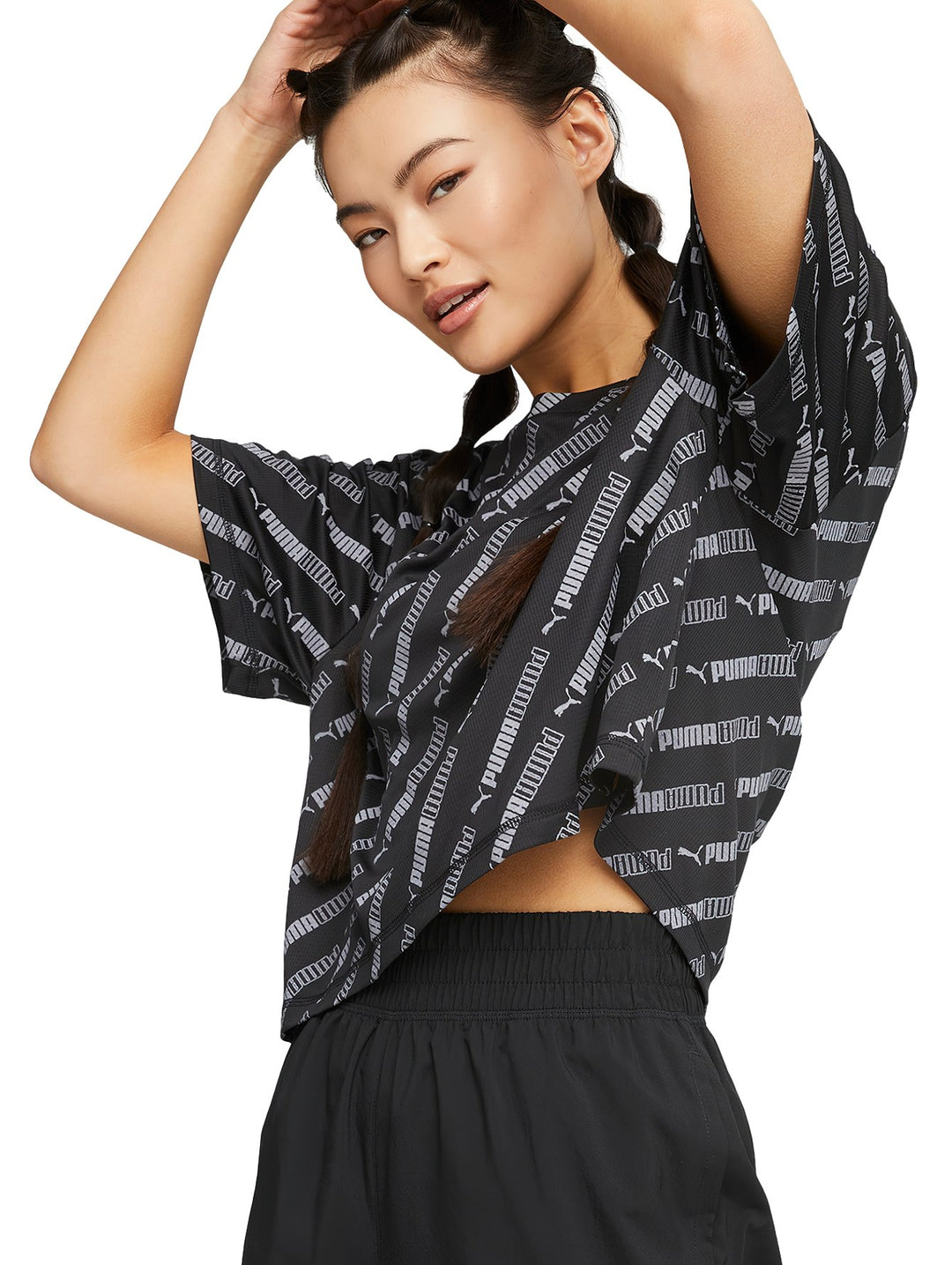 Camiseta crop deportiva PUMA color negro con estampado total de logotipos en gris oscuro.