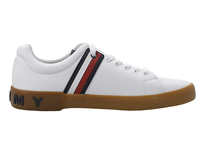 Tenis Tommy Hilfiger color blanco con suela marrón y franjas decorativas en azul y rojo en el lateral.