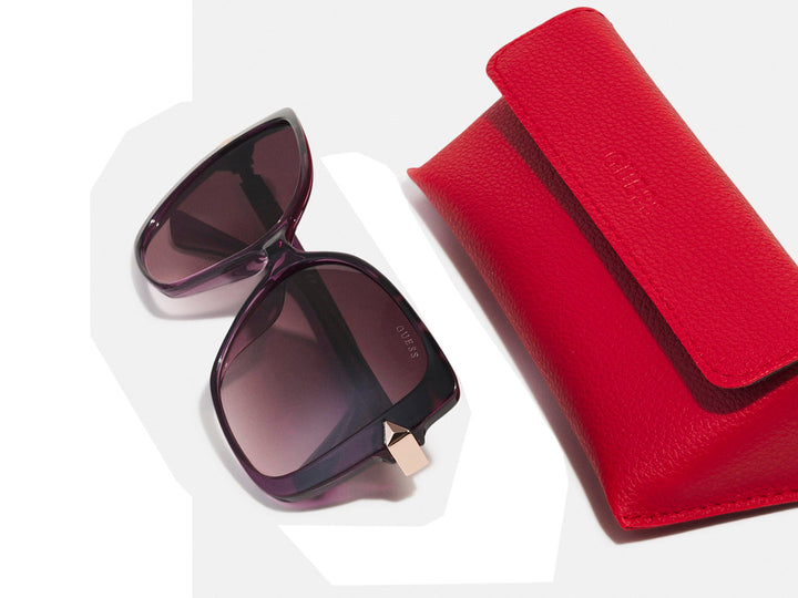 Lentes de sol Guess para mujer en color morado con cristales degradados y detalles laterales dorados.