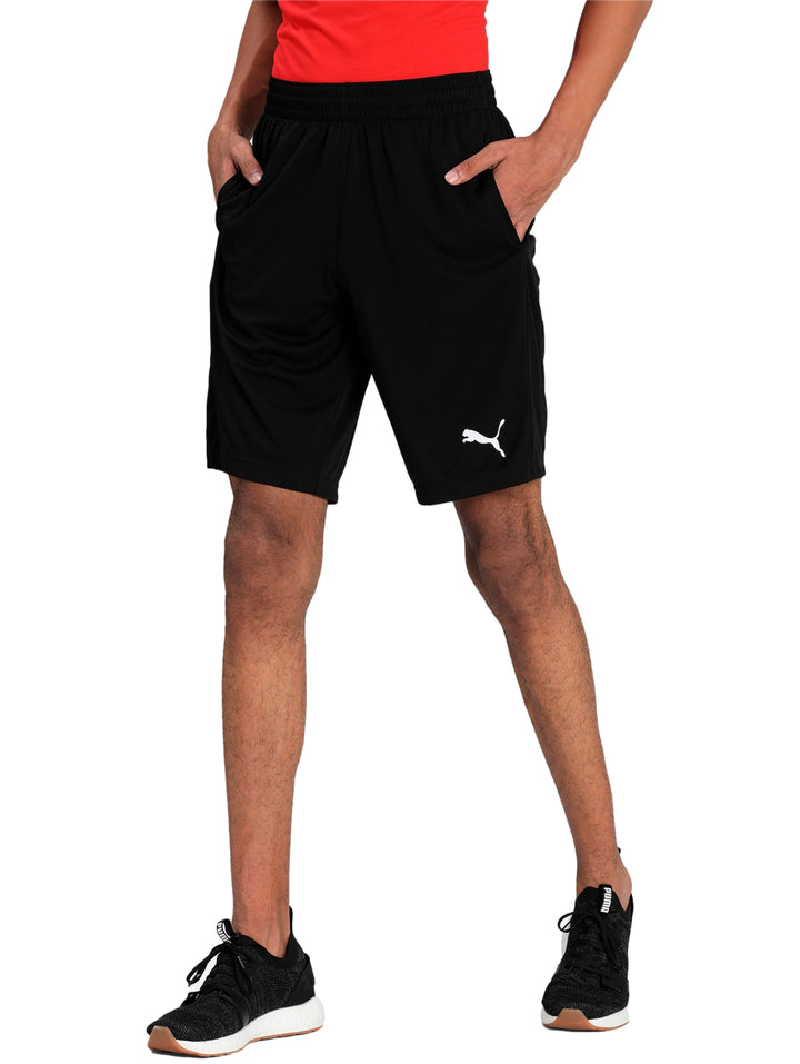 Hombre vistiendo shorts deportivos PUMA de color negro con logo blanco en la pierna izquierda.