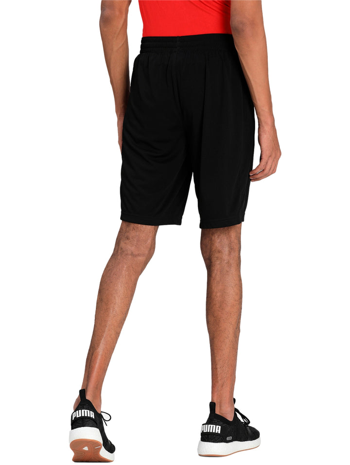 Hombre vistiendo shorts deportivos PUMA de color negro con logo blanco en la pierna izquierda.
