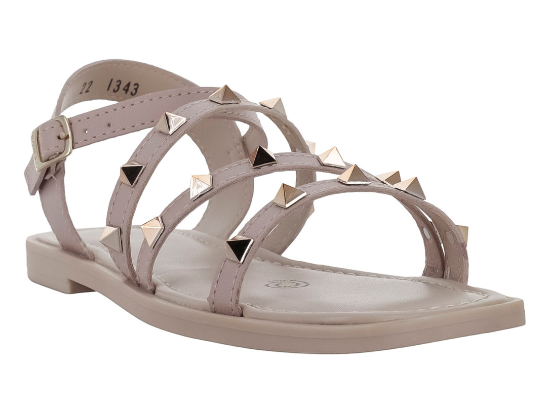 Sandalia plana color beige para niña con tiras decoradas con tachuelas doradas y cierre de hebilla.