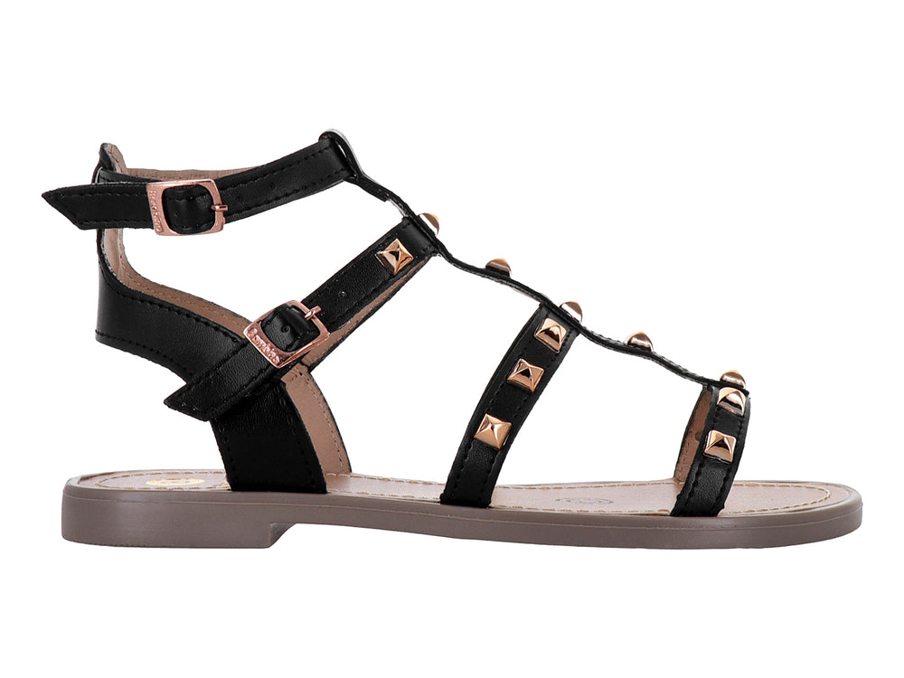 Sandalia negra para niña con tiras cruzadas, tachuelas doradas y suela color beige.