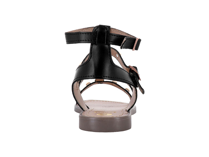 Sandalia negra para niña con tiras cruzadas, tachuelas doradas y suela color beige.