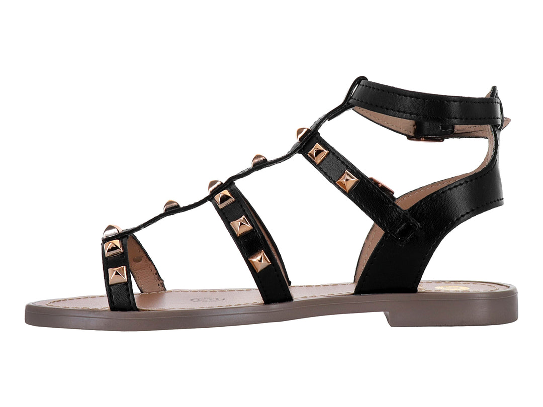 Sandalia negra para niña con tiras cruzadas, tachuelas doradas y suela color beige.