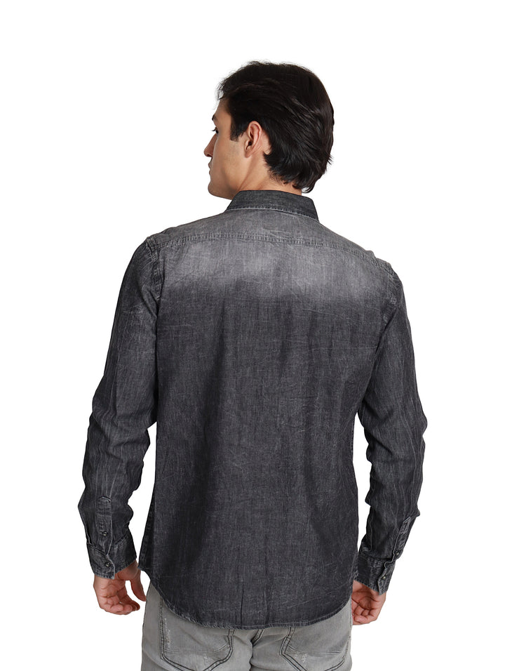 Hombre vistiendo camisa vaquera slim fit de color negro con manga larga y bolsillos frontales.