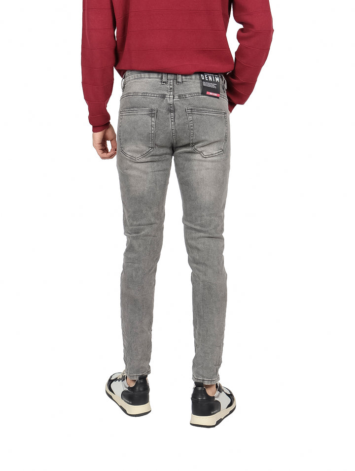 Hombre vistiendo pantalones jeans ajustados en color gris y un suéter rojo.