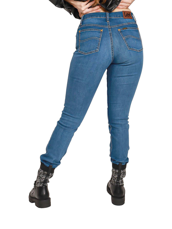 Mujer vistiendo jeans skinny color azul de cintura alta y botas negras.