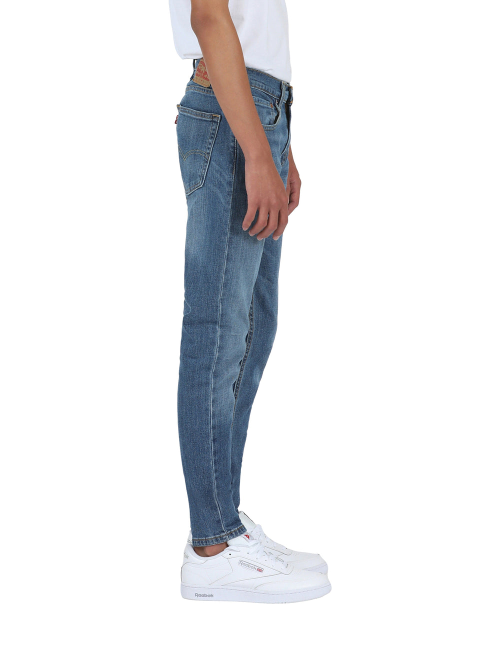 Hombre vistiendo pantalones Levi's de mezclilla azul claro en corte skinny taper y tenis blancos.