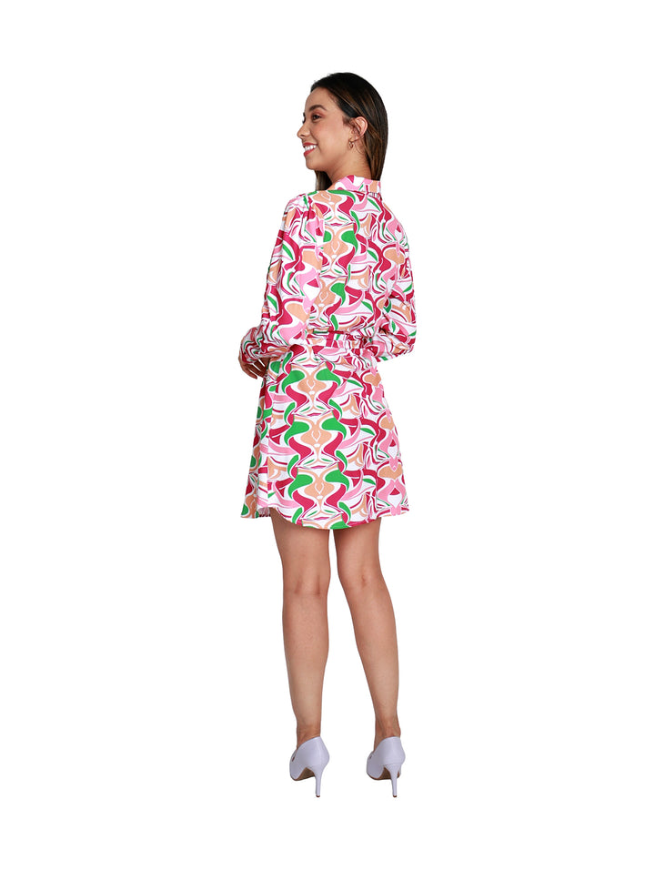 Mujer con vestido corto estampado en tonos fucsia, verde y blanco con manga larga.