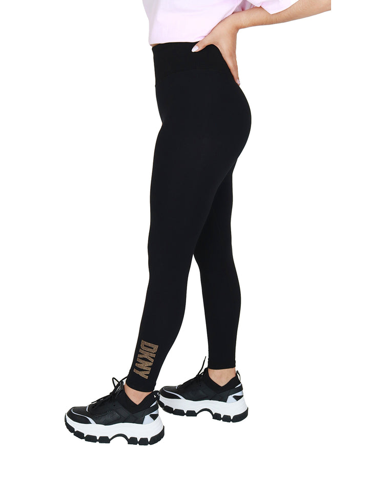Leggings negros de cintura alta marca DKNY con logo dorado en el tobillo.