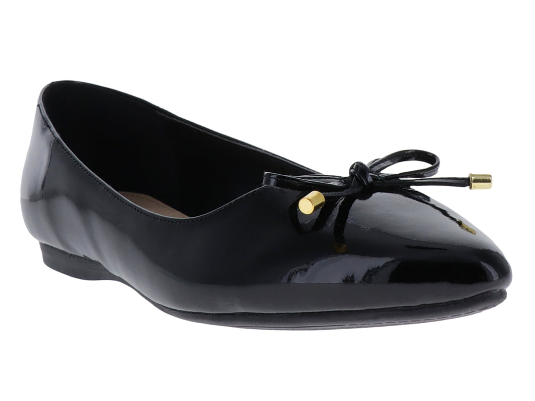 Zapato plano negro de charol brillante con un pequeño moño decorativo con puntas doradas.