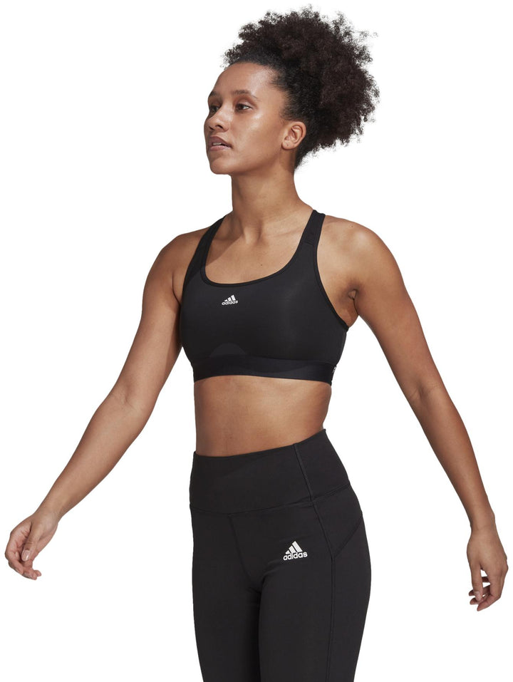 Mujer vistiendo un top deportivo corto color negro de la marca Adidas.