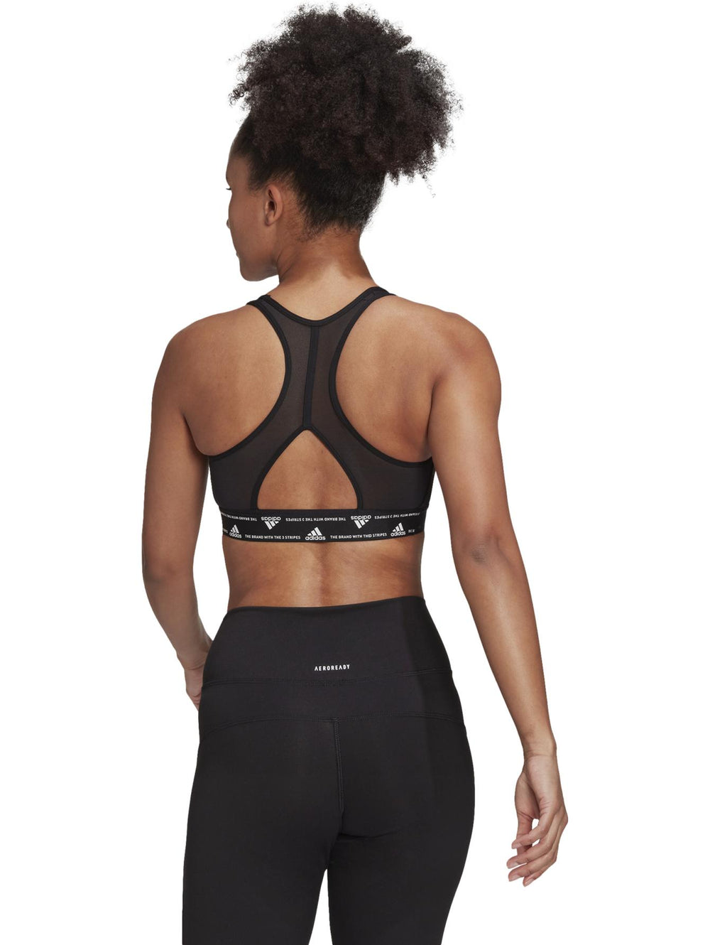 Mujer vistiendo un top deportivo corto color negro de la marca Adidas.