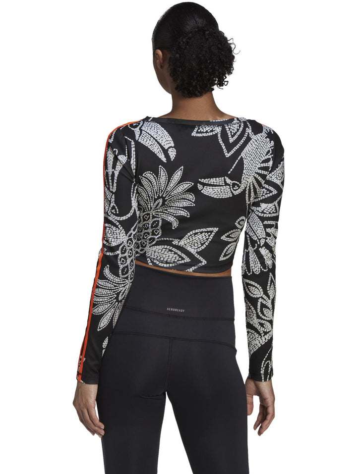 Crop top deportivo Adidas de manga larga en color negro con estampado blanco y franjas naranjas.