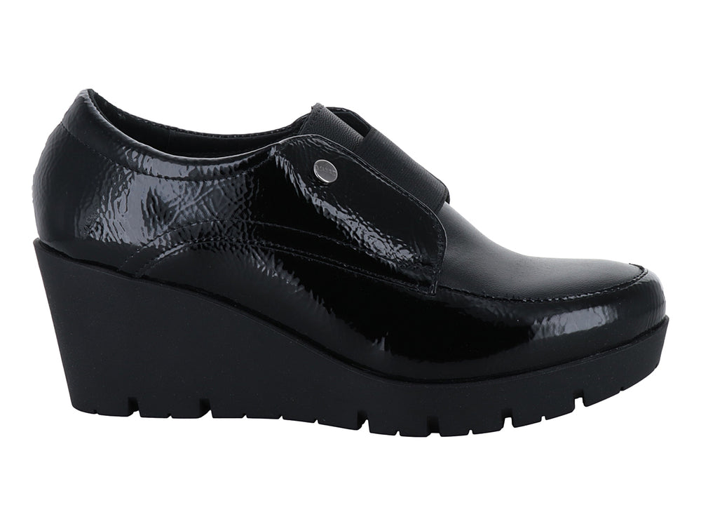 Zapato de piel negro con plataforma alta, acabado brillante y correa frontal con botón decorativo.