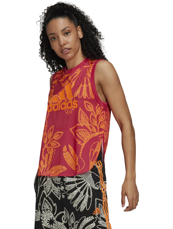 Mujer vistiendo camiseta Adidas sin mangas color Vivid Berry y naranja con estampado floral y pantalones a juego.
