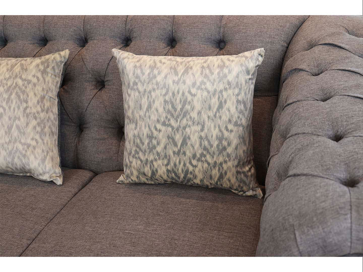 Juego de sala compuesto por dos sofás grises estilo Chesterfield con capitoné y cojines decorativos.