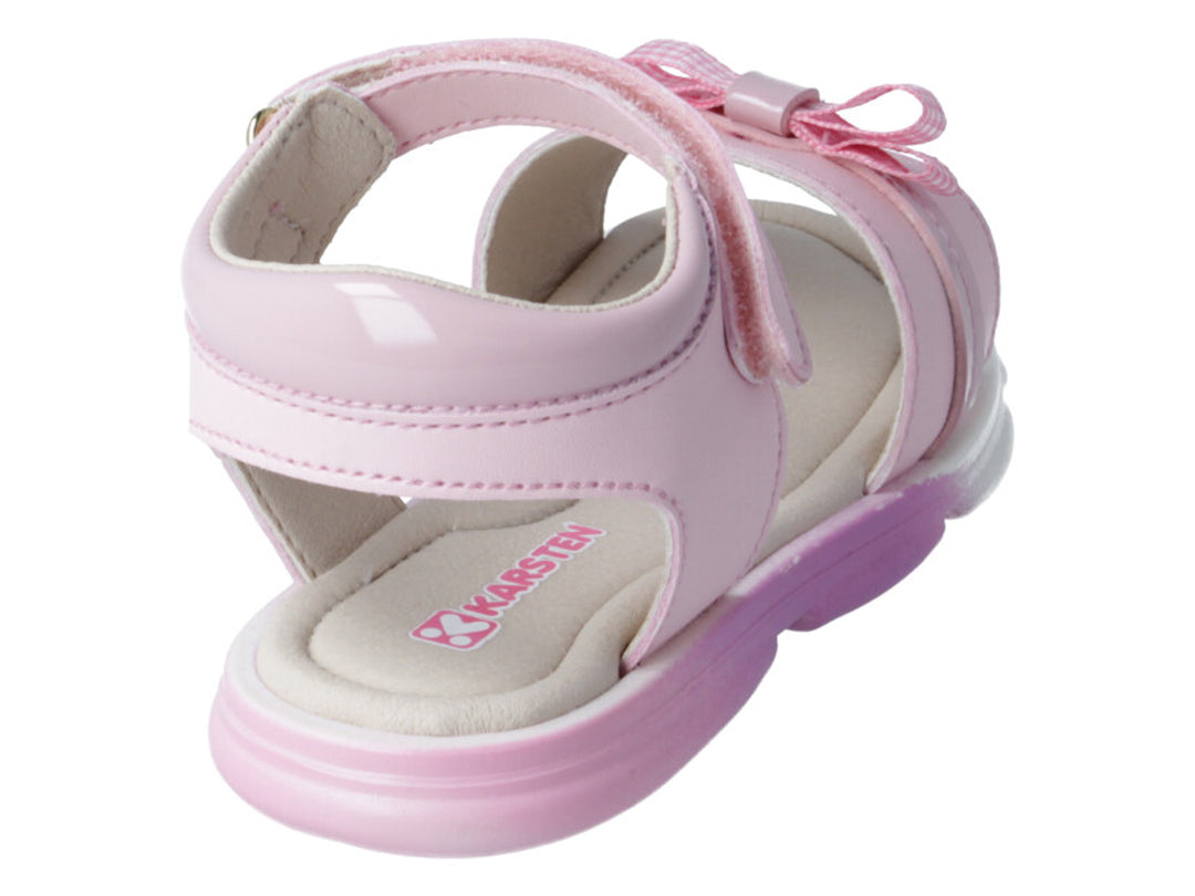 Sandalias rosas para niña con detalle de moño a cuadros y correa ajustable sobre fondo blanco.