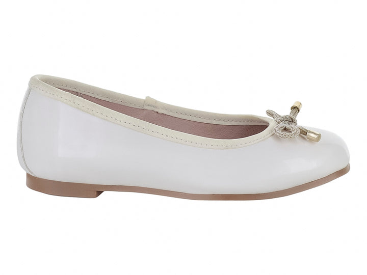 Zapato plano color hueso brillante para niña con moño decorativo y detalles dorados en la punta.