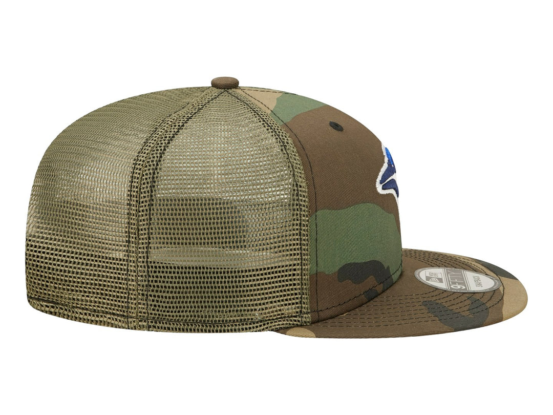 Gorra New Era con estampado de camuflaje en tonos verdes y cafés, visera plana y logo bordado al frente.