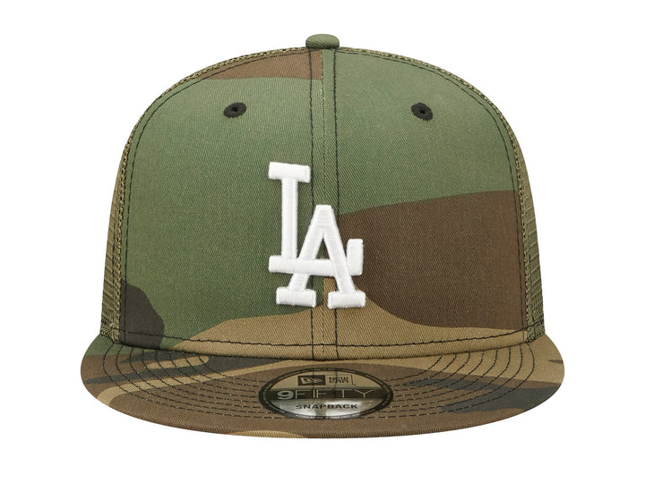 Gorra New Era con estampado de camuflaje en tonos verdes y cafés, visera plana y logo LA bordado en blanco.