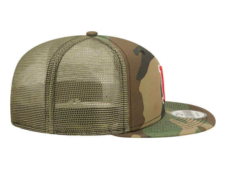 Gorra New Era estilo trucker con estampado de camuflaje y logotipo bordado en rojo y blanco al frente.