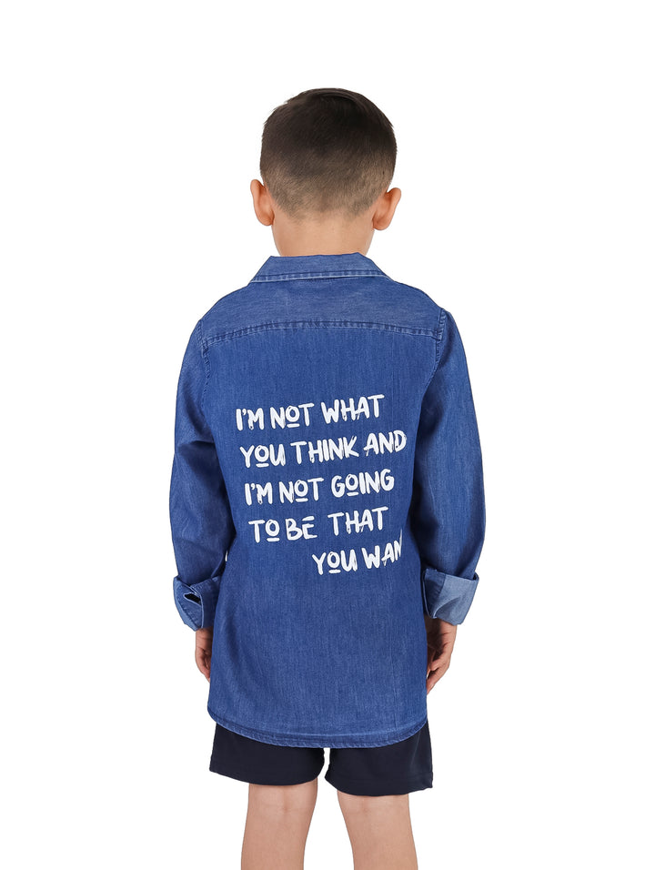 Niño vistiendo una camisa de mezclilla azul con botones y mangas remangadas.