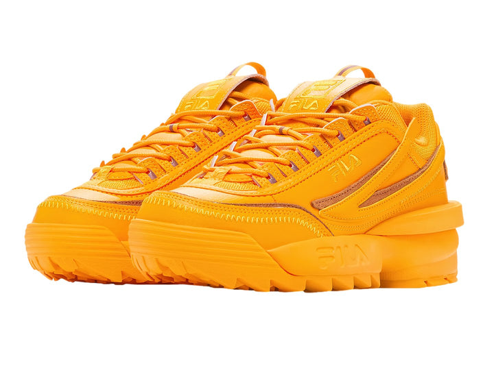 Tenis FILA Disruptor II Exp en color amarillo radiante y naranja con suela robusta y dentada.