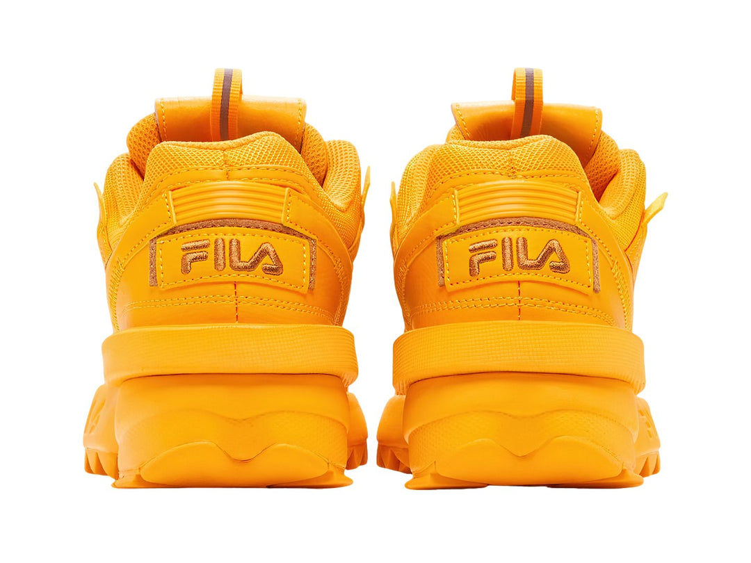 Tenis FILA Disruptor II Exp en color amarillo radiante y naranja con suela robusta y dentada.