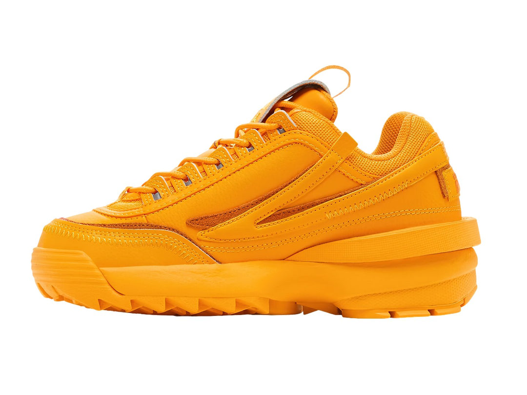 Tenis FILA Disruptor II Exp en color amarillo radiante y naranja con suela robusta y dentada.