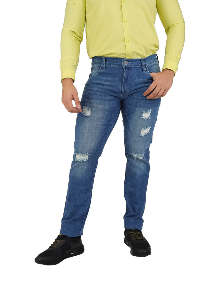 Hombre vistiendo pantalones jeans azules con efecto desgastado y rotos en las piernas.