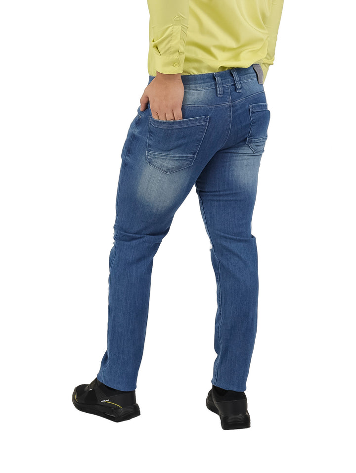 Hombre vistiendo pantalones jeans azules con efecto desgastado y rotos en las piernas.