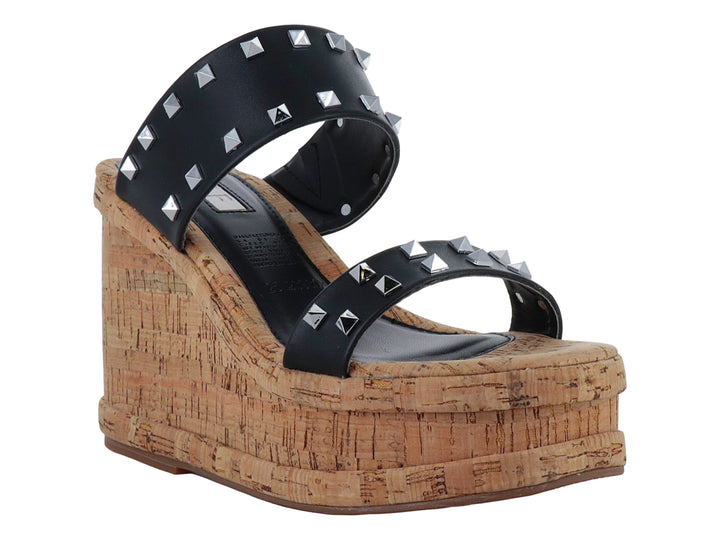 Sandalia negra de plataforma con tacón de corcho y tiras decoradas con tachuelas plateadas.