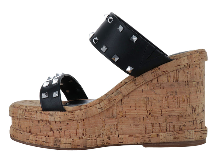 Sandalia negra de plataforma con tacón de corcho y tiras decoradas con tachuelas plateadas.