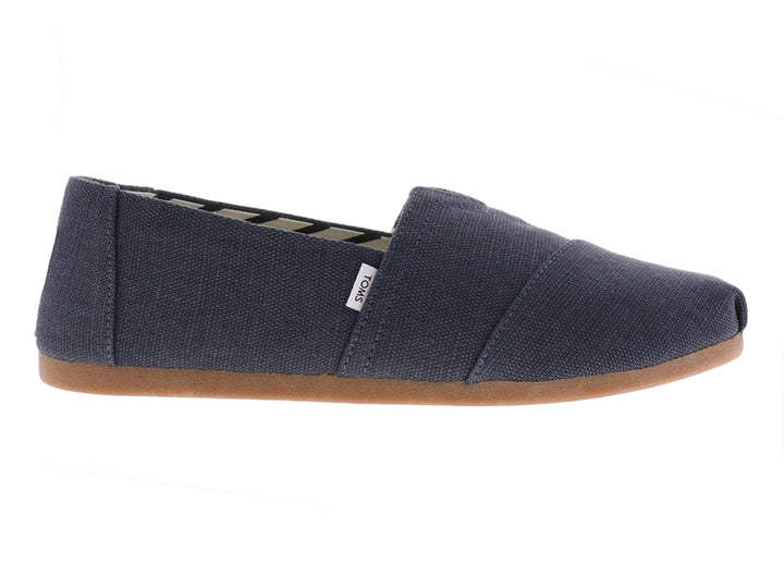 Zapato slip-on TOMS de color gris oscuro con suela color café y forro interior con patrón geométrico