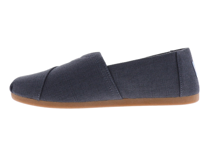 Zapato slip-on TOMS de color gris oscuro con suela color café y forro interior con patrón geométrico