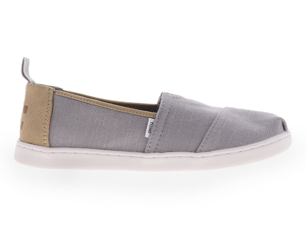 Zapato slip-on TOMS color gris con suela blanca y tejido texturizado para niño.