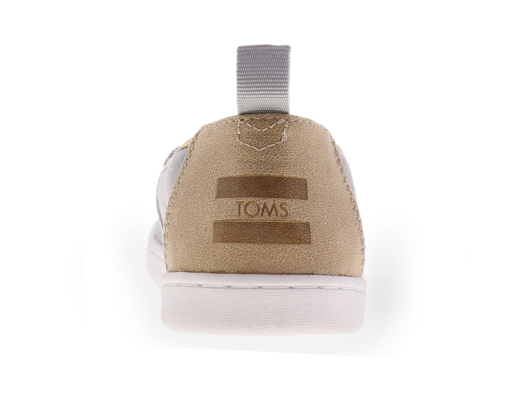 Zapato slip-on TOMS color gris con suela blanca y tejido texturizado para niño.