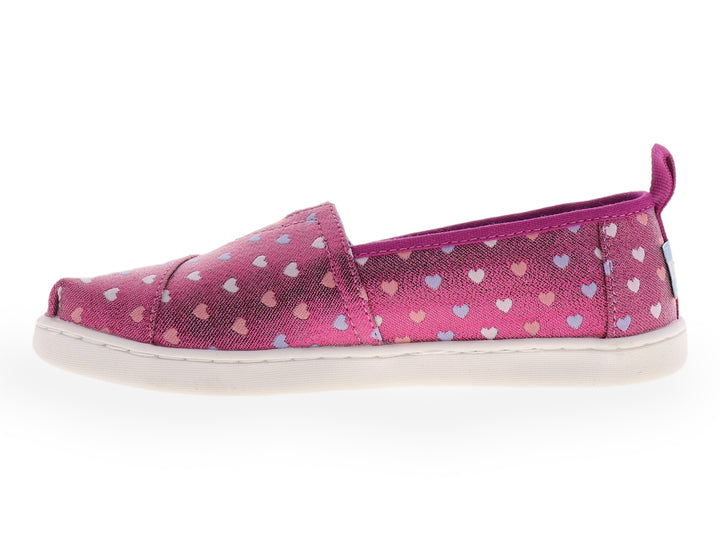 Zapato slip-on TOMS color fucsia brillante con estampado de corazones multicolores y suela blanca.