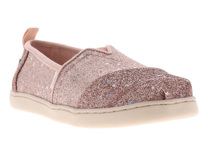 Zapato slip-on TOMS color oro rosa con acabado brillante y suela color crema.