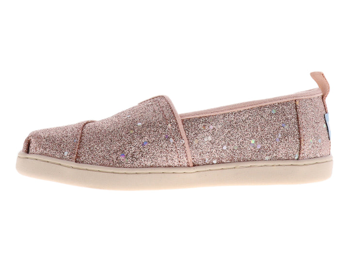 Zapato slip-on TOMS color oro rosa con acabado brillante y suela color crema.