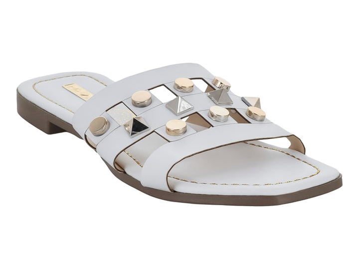 Sandalia blanca para mujer con tachuelas metálicas decorativas y suela plana.